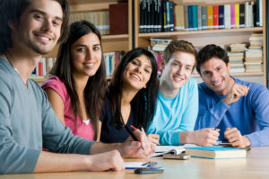 Happy group of young students studying together in a college lib